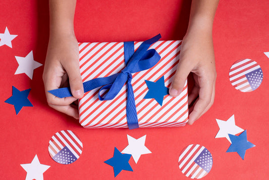 A person holding a gift wrapped in red, white, and blue paper