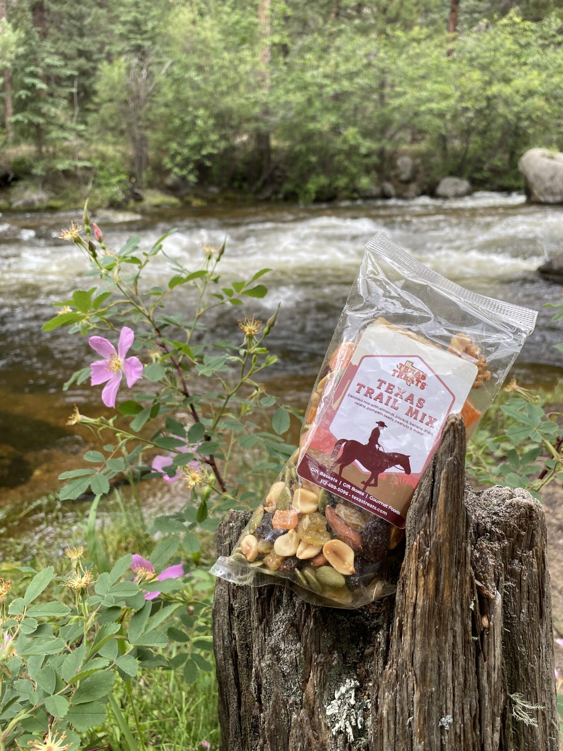 Texas Treats' Trail Mix perched on a log in nature.